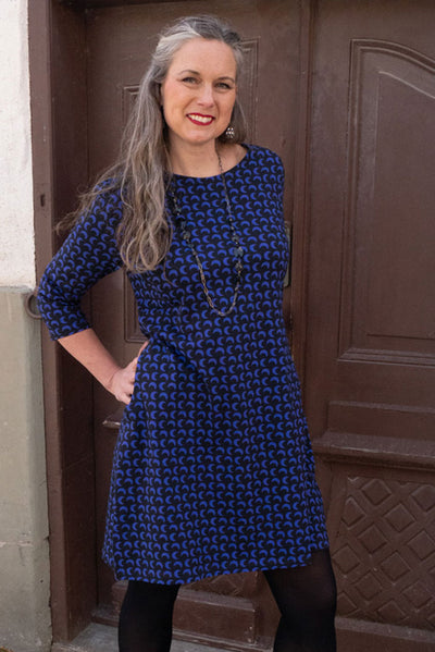 Klänning med trekvarts ärm och lätt rynk i högst upp på ärmen, rund båthals, fickor och längd till mitten på låret i tyg med blåa månar på svart grund från märket Esther & Inez