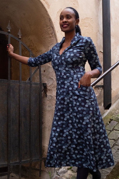 Figurnära klänning med v-urringning och schalkrage i blåa nyanser med paraplymönster som prickar, trekvarts ärm, fickor och längd till vaden från märket Esther & Inez